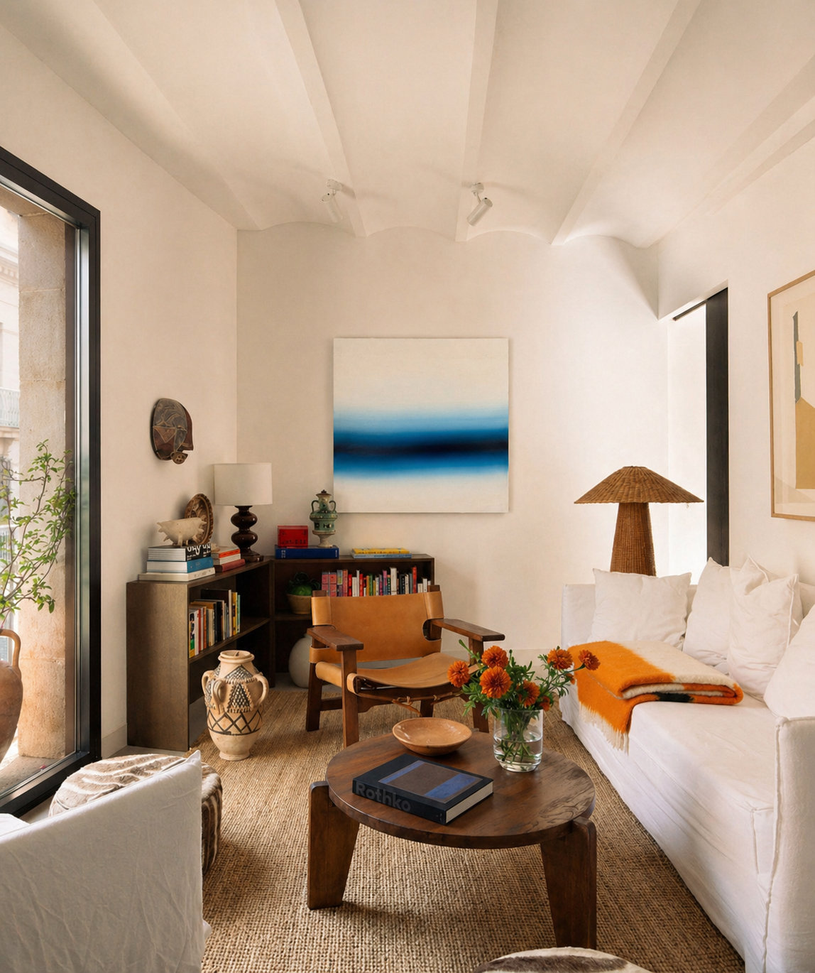 Modern living room with white sofa, wooden coffee table, and abstract art on wall, featuring contemporary artworks by welsh artist Elfyn Lewis. 
