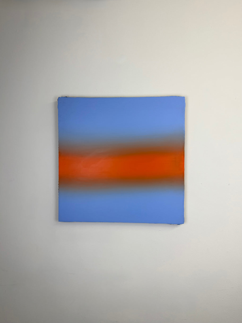 Original minimalist artwork by Welsh Artist Elfyn Lewis. Acrylic paint on MDF board to create a calming yet striking appearance through a dramatic warm orange band, radiating amongst a calm light blue at the top and base, reflecting feelings of a diminishing sunset landscape. 