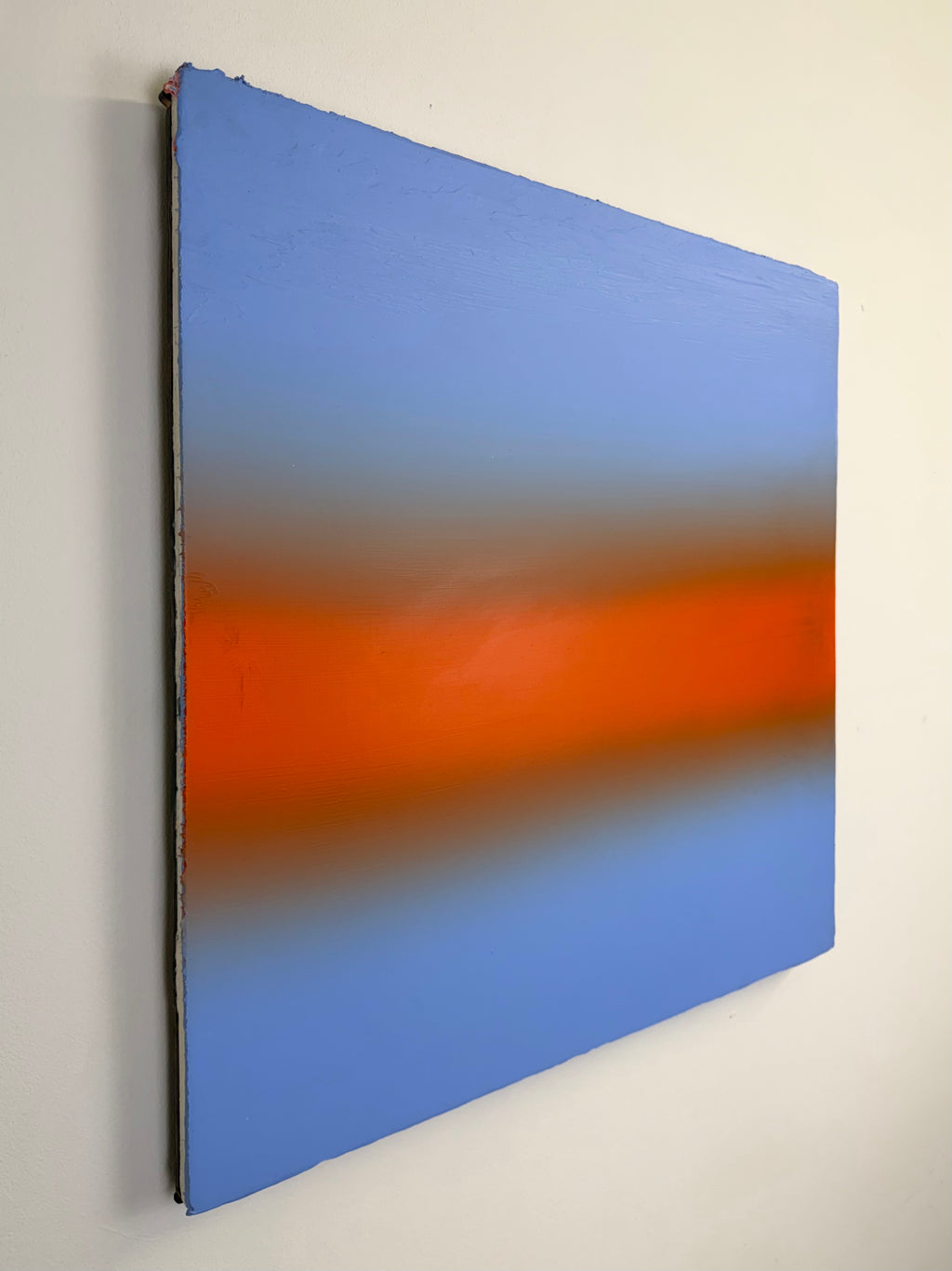 Original minimalist artwork by Welsh Artist Elfyn Lewis. Acrylic paint on MDF board to create a calming yet striking appearance through a dramatic warm orange band, radiating amongst a calm light blue at the top and base, reflecting feelings of a diminishing sunset landscape. 