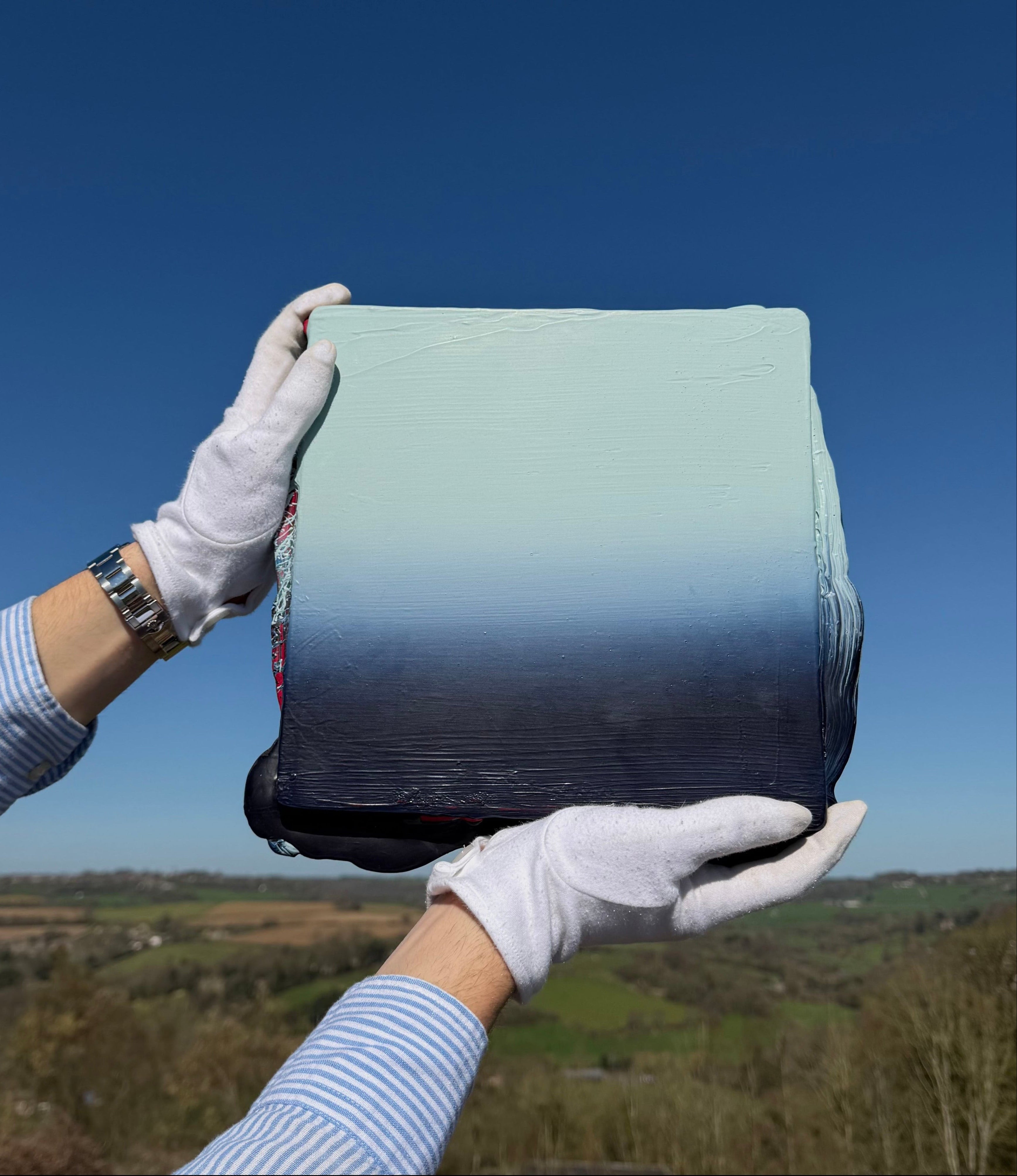 Holding an original piece of Elfyn Lewis up to the blue sky, Contemporary abstract artist renowned for his abstraction and landscape-inspired artworks. 