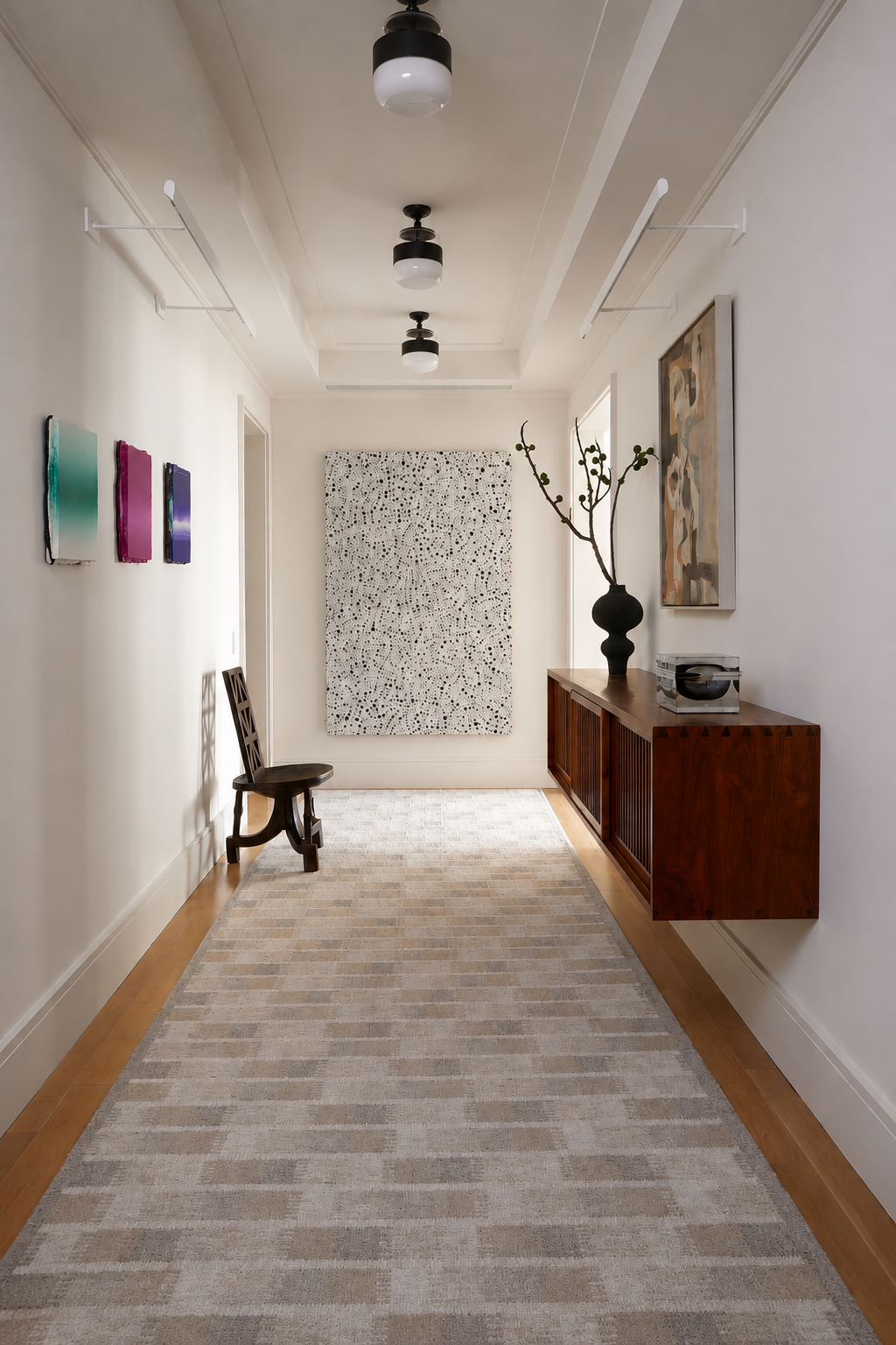 Modern hallway with a wooden console table, chair, and abstract art on the walls.