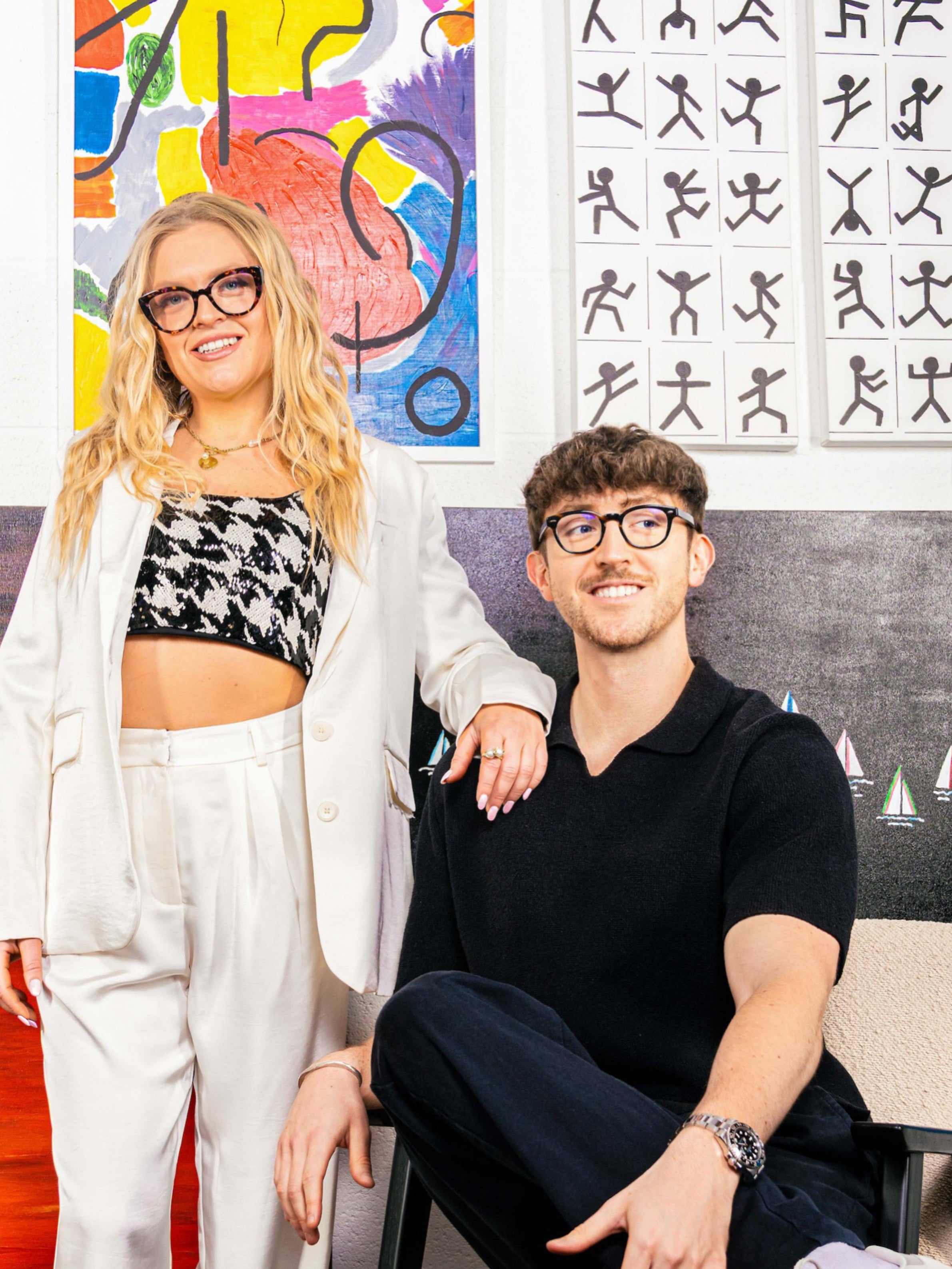 Bella and Ollie Art Curators standing in front a gallery wall of curated abstract artworks. 