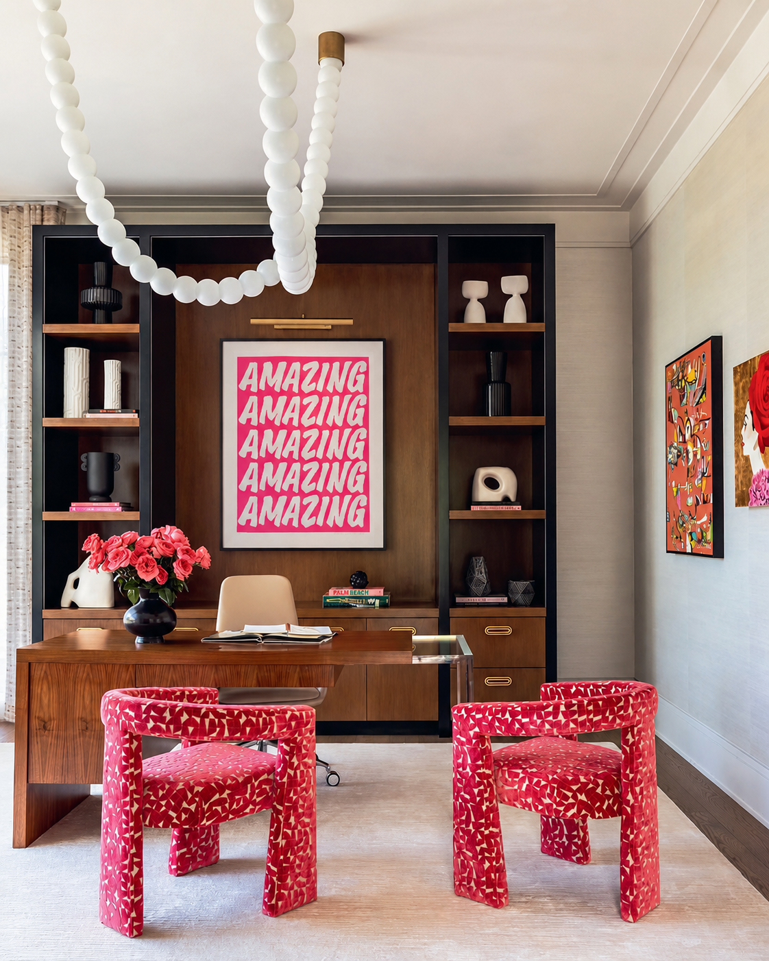 Modern office with red patterned chairs, wooden desk, and 'AMAZING' poster.