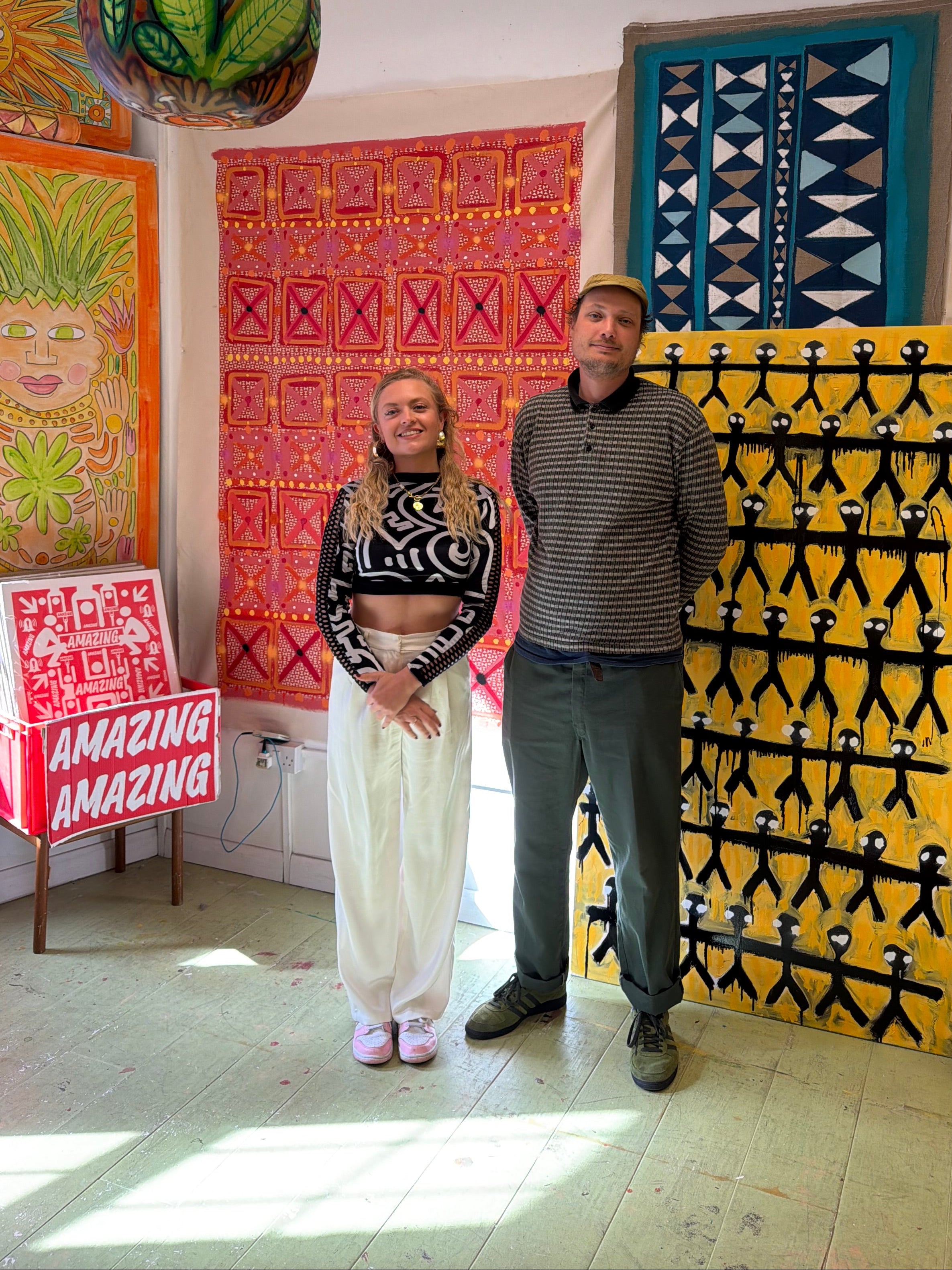 Two people standing in a room with colorful rugs on the floor.