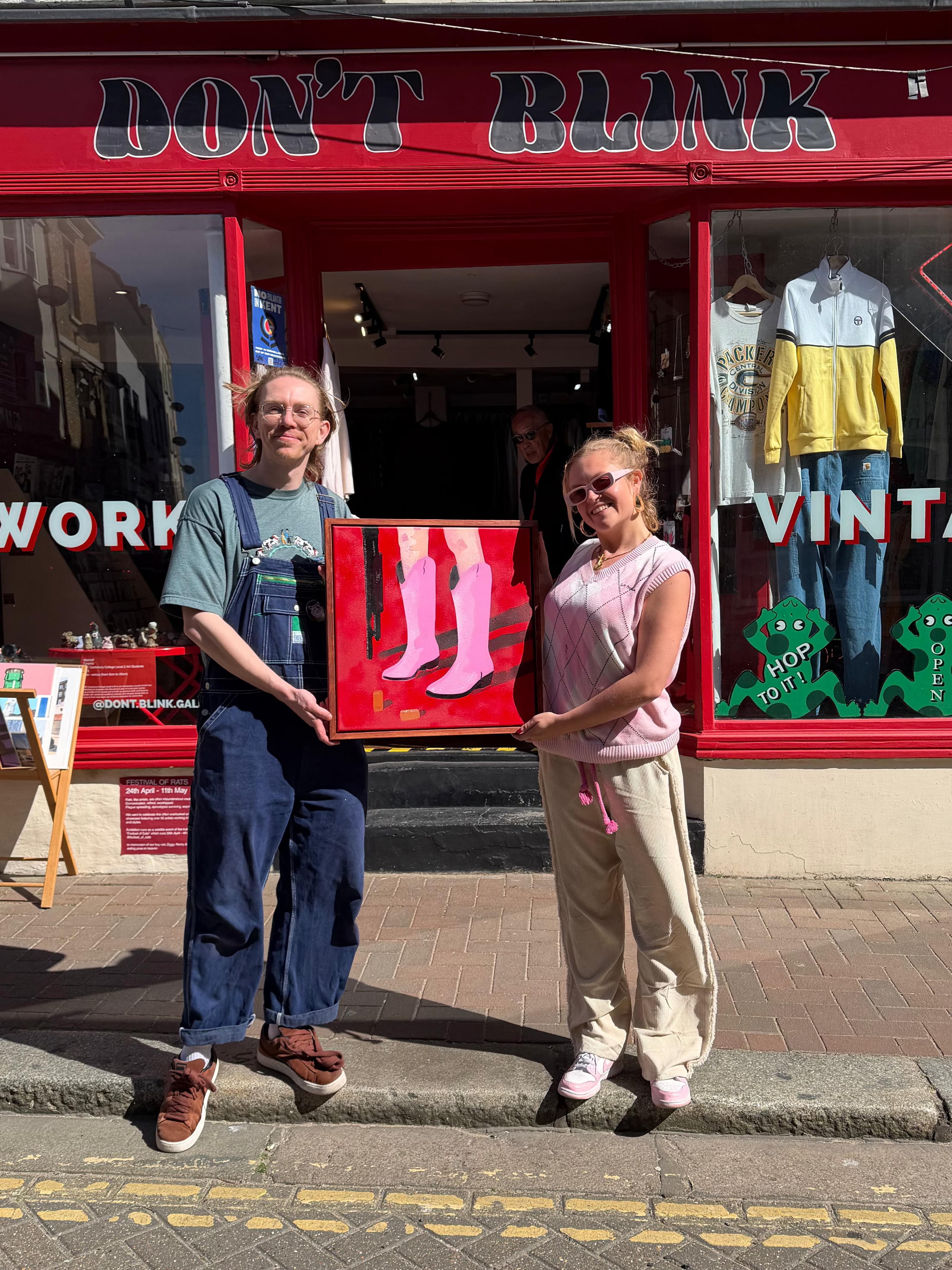 Artist Maximillan Boxer holding a framed artwork in front of a vintage store with 'Don't Blink' shop and gallery  in Margate. 