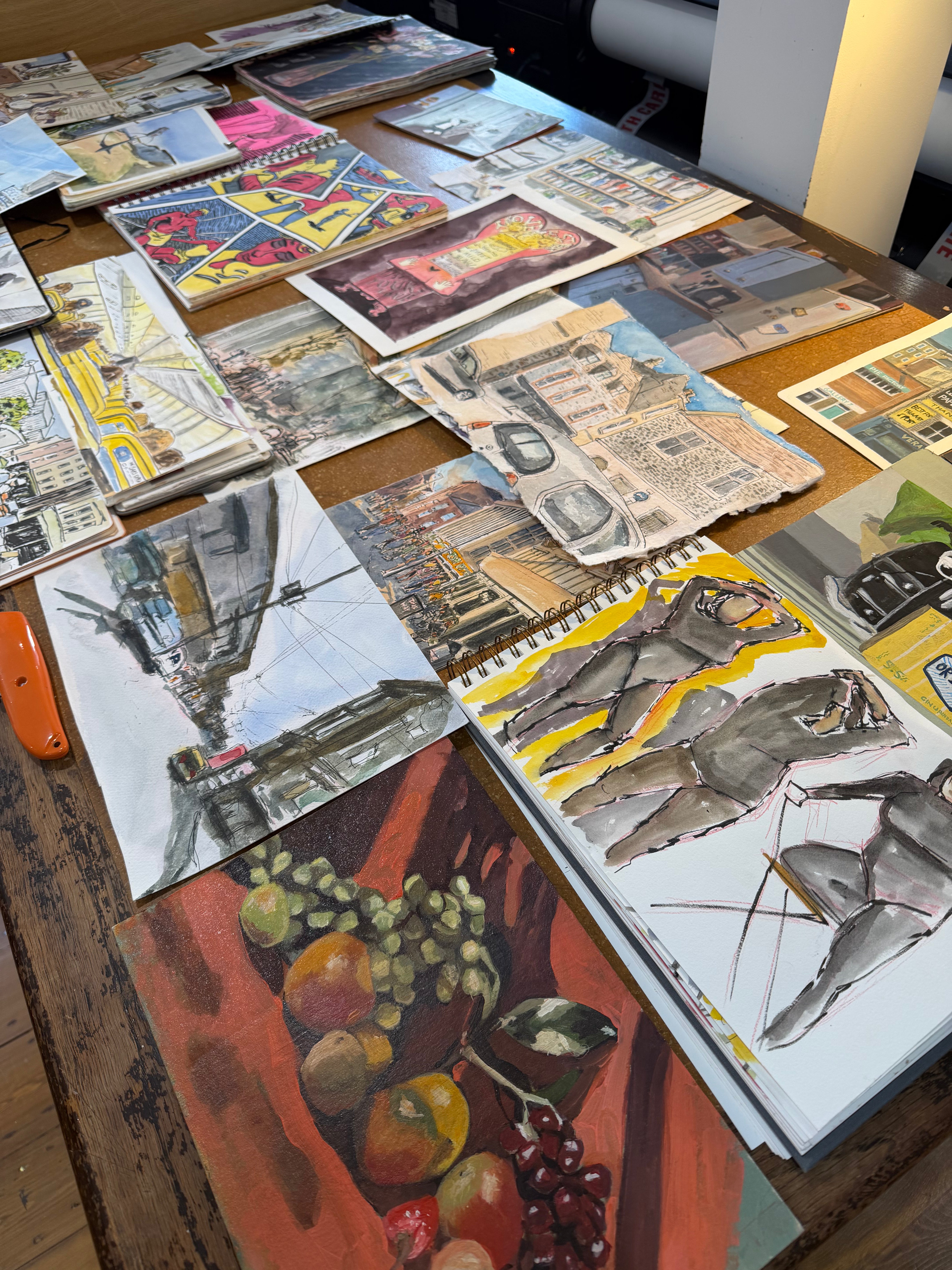 Collection of art sketches of margate by artist Maximillian Boxer on a table, including landscapes and still life scenes.