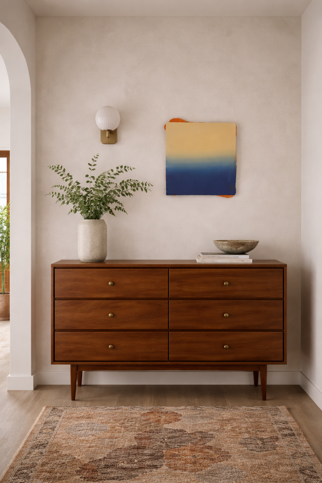 Wooden dresser in a room with a plant, wall art, and rug.