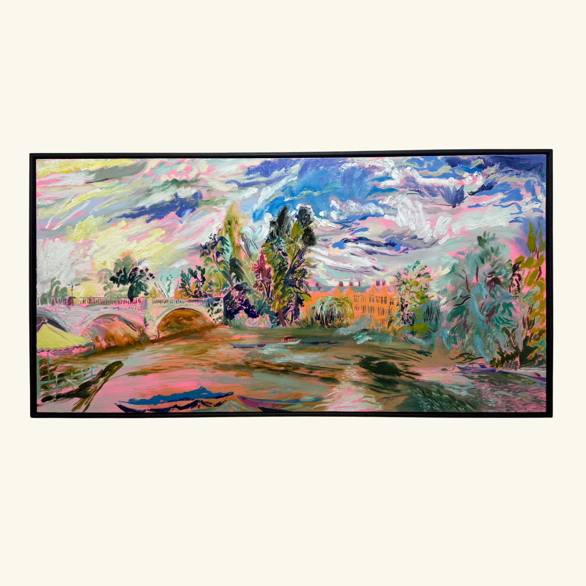 A framed landscape painting featuring a colorful river thames scene with trees, a bridge, and a pinkish-orange building under a dramatic blue and pink sky. The River Carries the Light 2026 by Hannah Rollings, original contemporary landscape painting of the River Thames